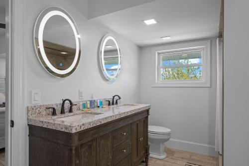 a bathroom with a sink and a toilet and two mirrors at Shell Hill house Waterfront, kayaks, grill, pier in Sealevel