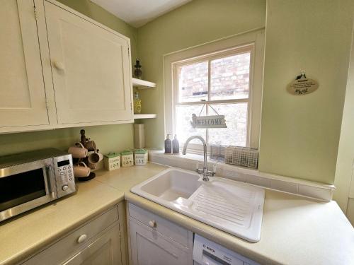 a kitchen with a sink and a microwave at Prospect Cottage in Hythe
