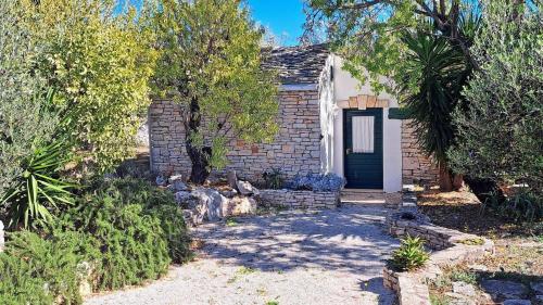 a brick house with a black door and trees at House Darin dvor in Vela Luka