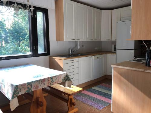 a kitchen with white cabinets and a table and a window at Purola holiday cottage by the lake Kivijärvi in Kivijärvi
