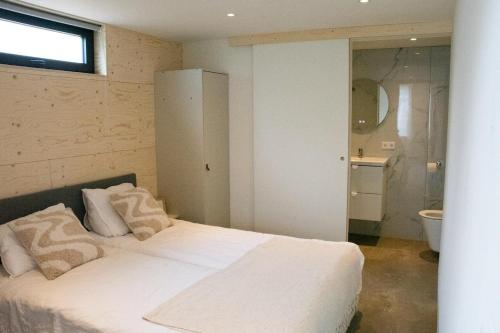 a bedroom with a bed with white sheets and pillows at NoSa Sleep, Sfeervol vakantiehuis in Grijpskerke in Grijpskerke