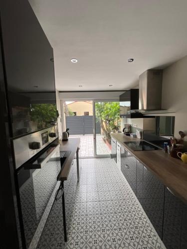 une cuisine avec comptoirs noirs et une grande fenêtre dans l'établissement MAISON MODERNE ET CONFORTABLE - Proche de la mer - Arrivée autonome, à Canet