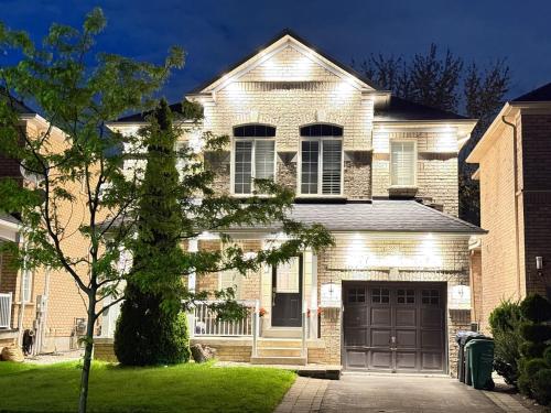 a brick house with a garage in a yard at Welcome to Your Home Away From Home! in Mississauga