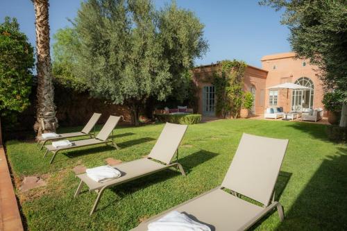 a group of lawn chairs sitting in the grass at Luxueuse villa VALERIA avec gouvernante in Chaibate