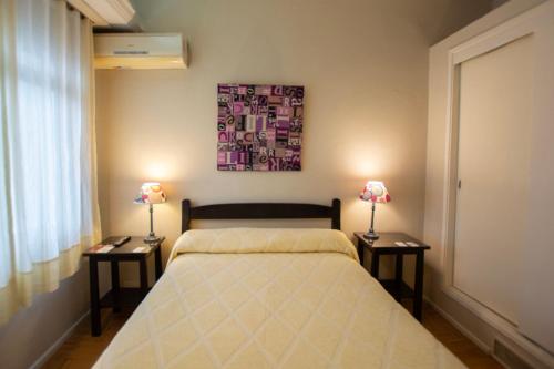 a bedroom with a bed and two tables with lamps at Hotel Ro Che Hil Tandil in Tandil