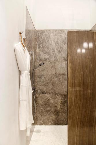 a bathroom with a shower with a white robe at Casa de la Renta By Mustique in Cartagena de Indias