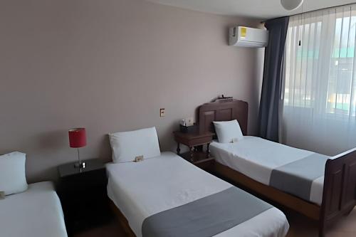 a hotel room with two beds and a window at LA CASA de los RIVAS, AA, amplia, cómoda, céntrica in Tepic