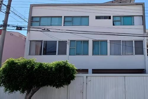 a white building with a fence and a tree at LA CASA de los RIVAS, AA, amplia, cómoda, céntrica in Tepic