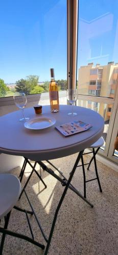 una mesa con dos copas y una botella de vino en La Frégate Town Centre and Beach, en Le Grau-du-Roi
