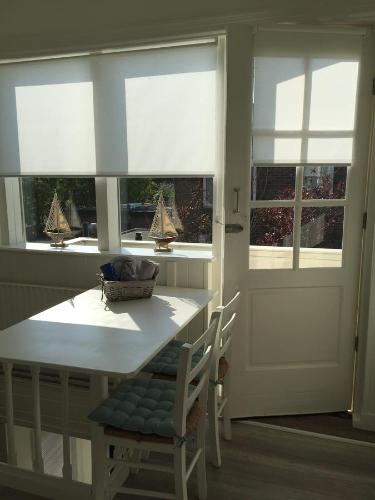 een keuken met ramen en een tafel en stoelen bij Studio De Laan in Zandvoort