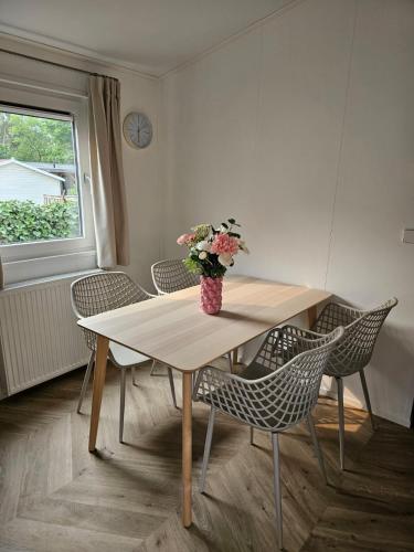 a dining room table with chairs and a vase of flowers at Luxe chalet op 5-sterren camping met comfortabel ingerichte veranda - parkkosten zijn inbegrepen in Sevenum