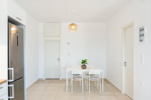 a white dining room with a white table and chairs at Thanos' seaside suite in Oropós