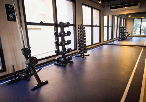 a gym with rows of exercise equipment in a room with windows at Urbà Home Stay by Housi in Goiânia
