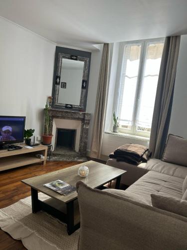 a living room with a couch and a table and a mirror at Appartement calme avec jardin in Nancy