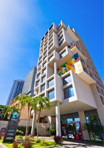 a tall white building with colorful windows and palm trees at Urbà Home Stay by Housi in Goiânia
