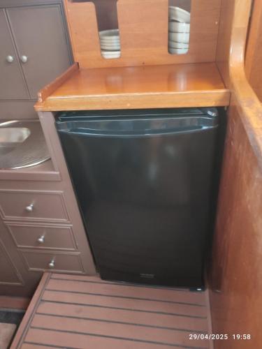 a small kitchen with a black refrigerator and cabinets at Romantic sailboat in Valencia
