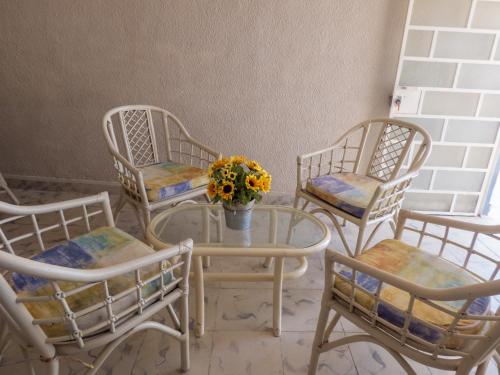 a group of chairs and a table with a vase of flowers at Hotel Boutique Flores y Gemas in Mérida