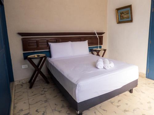 a bedroom with a bed with two white towels on it at Hotel Boutique Flores y Gemas in Mérida