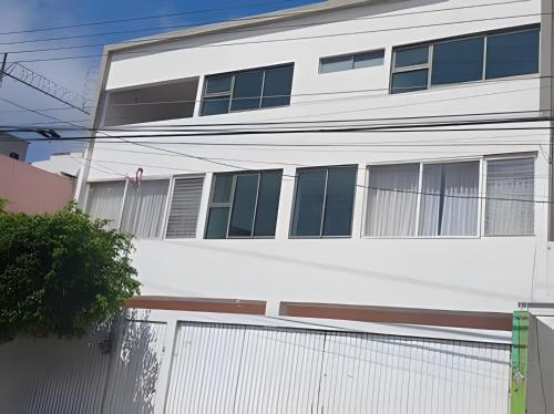 a white building with a fence in front of it at SUITE Clavel, AA, cocineta, baño privado, ubicació in Tepic