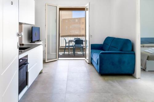 a living room with a blue couch and a kitchen at Blu Lodge Guest House in Alghero