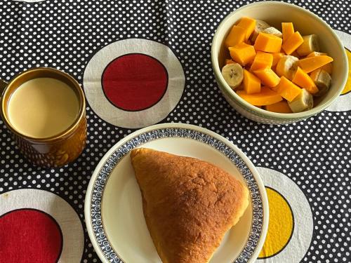 a table with a plate of bread and a bowl of fruit at Milemeleni Guesthouse in Lushoto