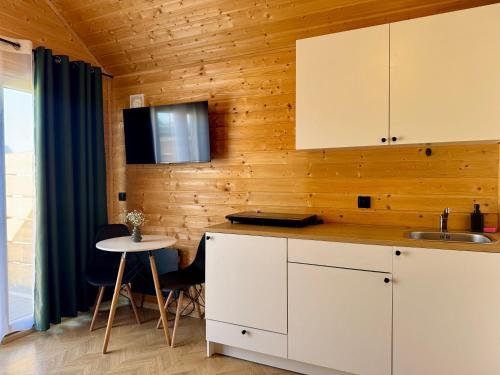 a kitchen with white cabinets and a small table at Wooden studies in Piotrowice