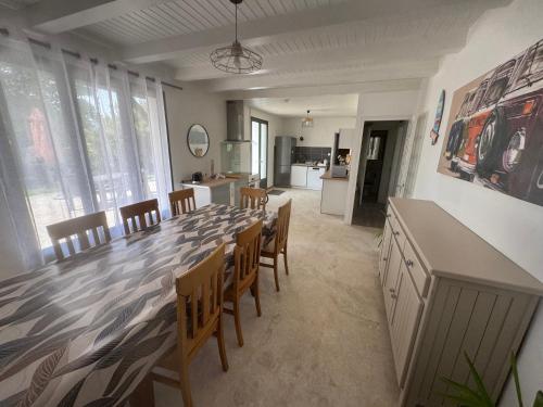 une grande salle à manger avec une longue table et des chaises dans l'établissement Villa Family Surf sur un terrain arborée et clos, calme et repos, à Longeville-sur-Mer