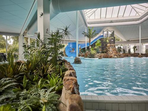 a swimming pool in a building with a water slide at Farmhouse in Limburg with Sauna & Pool in Roggel