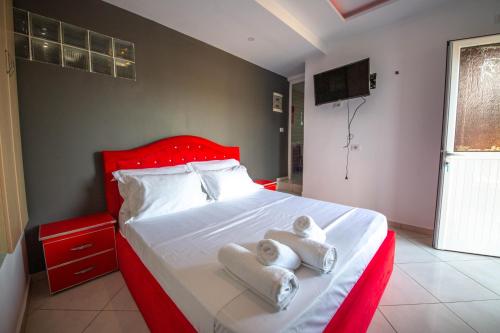 a bedroom with a red bed with towels on it at Noemi's Hotel Ksamil in Ksamil