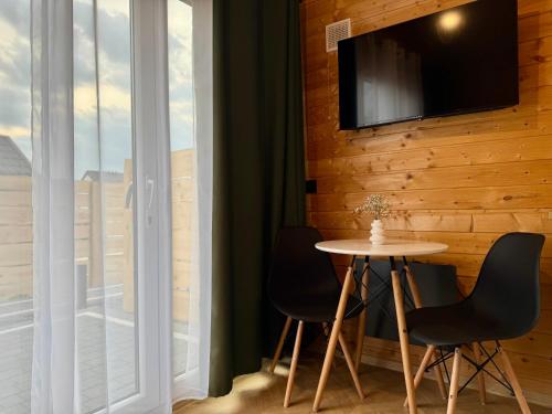 a room with a table and two chairs and a tv at Wooden studies in Piotrowice