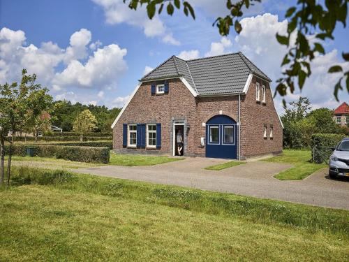 a brick house with a blue door on a street at Farmhouse in Limburg near Maasplassen in Roggel