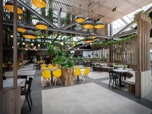 a restaurant with tables and yellow chairs and lights at Farmhouse in Limburg near Maasplassen in Roggel