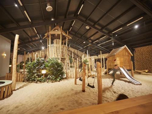 a playground in a building with a slide and a house at Farmhouse in Limburg with Sauna & Whirlpool in Roggel
