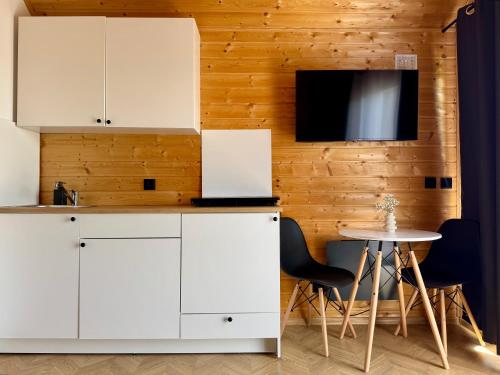 a kitchen with white cabinets and a table and a tv at Wooden studies in Piotrowice