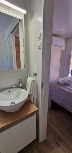 a bathroom with a sink and a mirror and a bed at Mobile home K in Biograd na Moru
