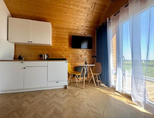 a kitchen with white cabinets and a large window at Wooden studies in Piotrowice