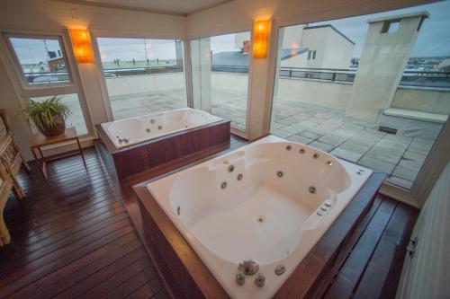 une grande salle de bains avec deux baignoires et une grande fenêtre dans l'établissement Hotel Patagonia, à Río Gallegos
