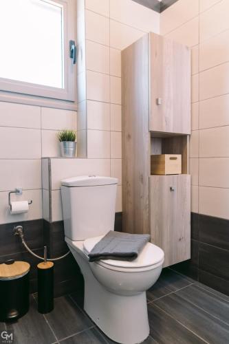a bathroom with a white toilet and a window at GMhouse in Perdika