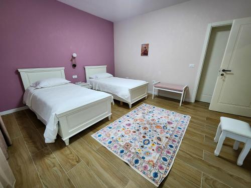 a bedroom with two beds and a rug at Vila Ermoza in Korçë