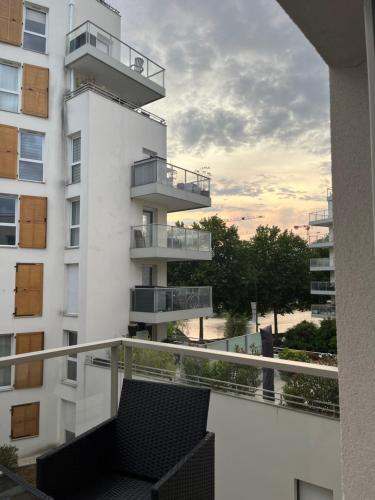une vue du balcon d'un bâtiment blanc avec une chaise dans l'établissement Appartement cosy vue sur Seine, à Alfortville
