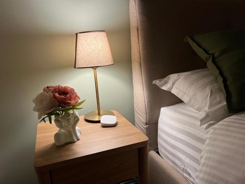 a table with a lamp and a vase with flowers on it at ATK Apartment T1 Airport Bus Station in Tallinn