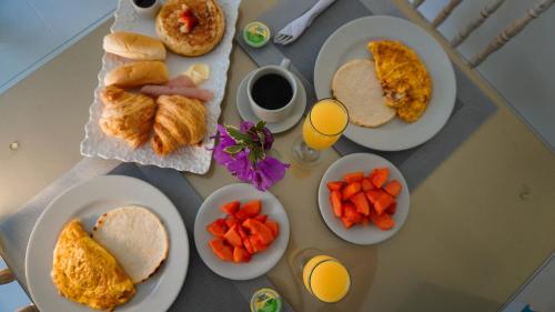 Malik Hotel Boutique في كالي: طاولة مليئة بأطباق طعام الإفطار وعصير البرتقال