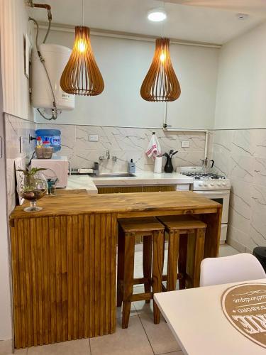 a kitchen with a wooden counter and two lights at Aloha Nelly - Departamento de alquiler por día in Trelew