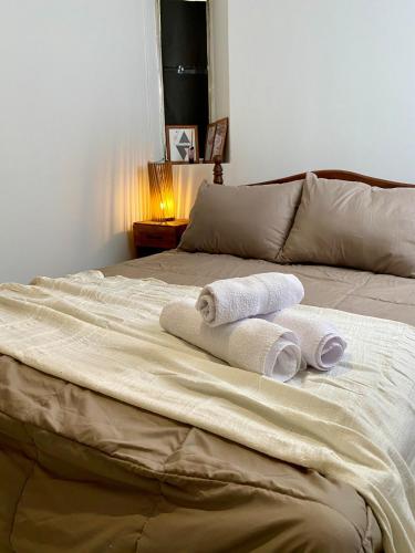 a bed with two rolled towels on top of it at Aloha Nelly - Departamento de alquiler por día in Trelew