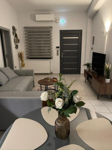 a living room with a couch and a table with flowers at Trifhouse - Village and Sea escape in Neochórion