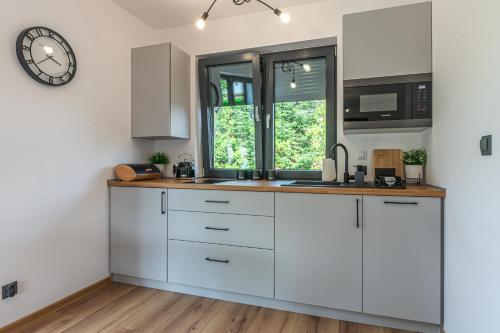 a kitchen with white cabinets and a clock on the wall at Domek z Widokiem in Zator