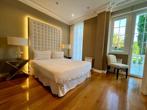 a bedroom with a large white bed and a chair at Autentico lujo, Villa Stylish Host Cantabria. in Camargo