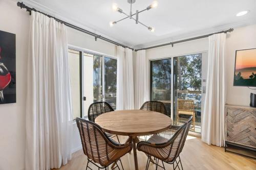 a dining room with a table and chairs and windows at The Andalusite - Oceanfront Steps from the Sand in Los Angeles