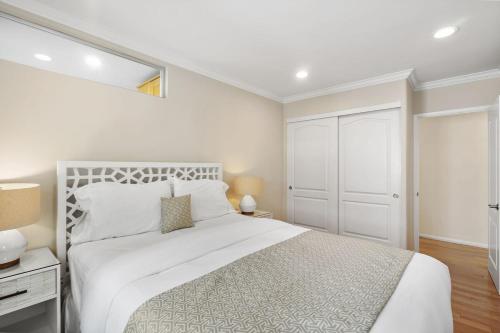 a white bedroom with a white bed and a window at The Andalusite - Oceanfront Steps from the Sand in Los Angeles