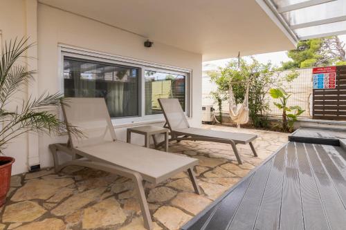 two white chairs sitting on a patio at Rafia Loft Loutraki - Heated Pool & Billiard I Beach in Loutraki